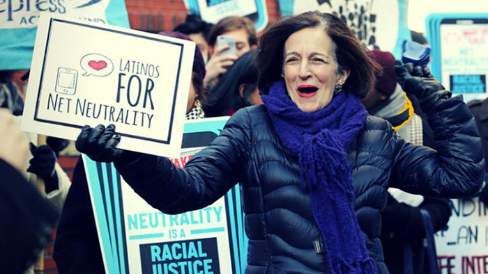 Former FCC Commissioner Gloria Tristani holding a sign reading “Latinos for Net Neutrality”
