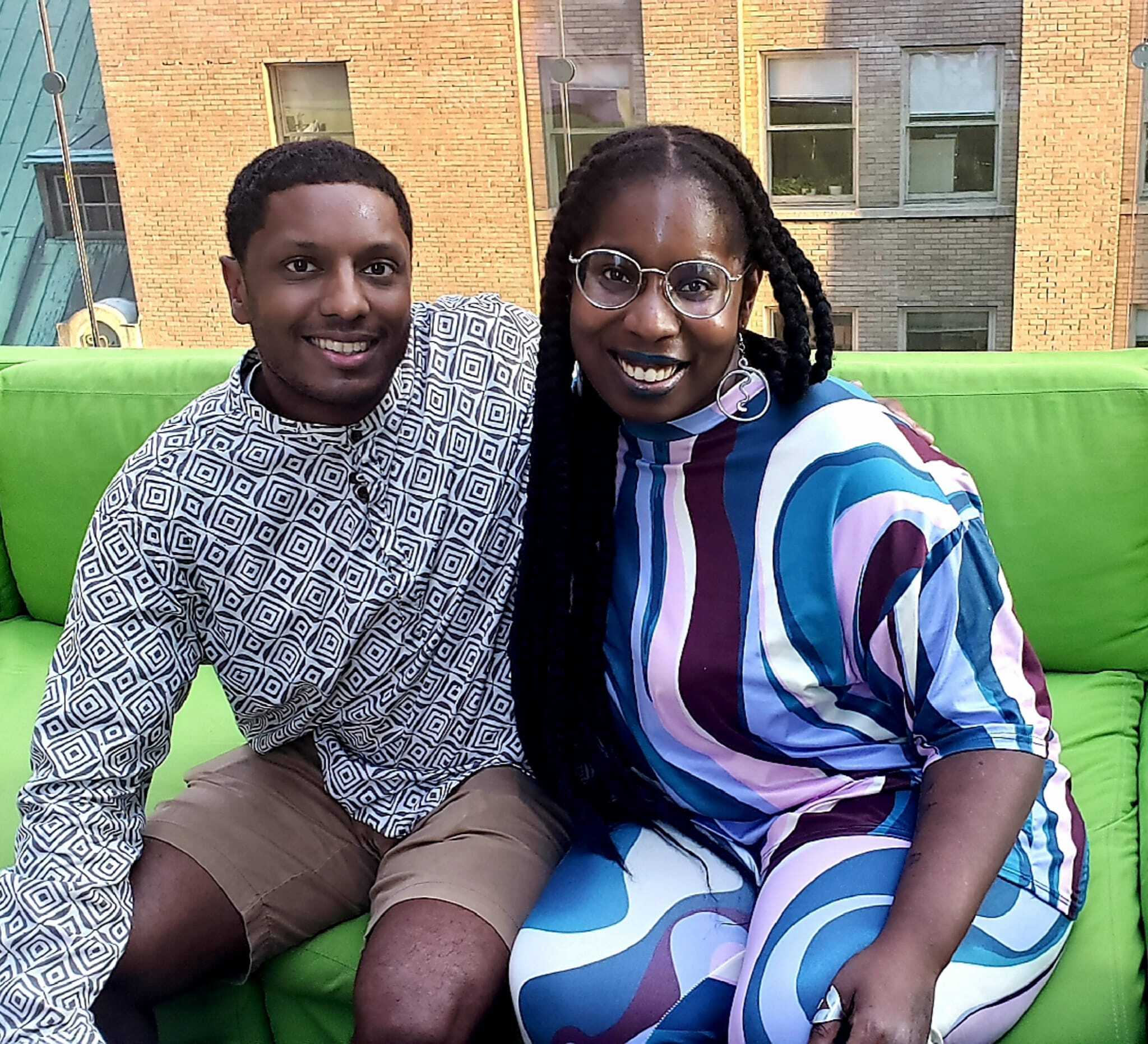 Free Press' Tauhid Chappell and Cassie Owens sitting outside on a green couch