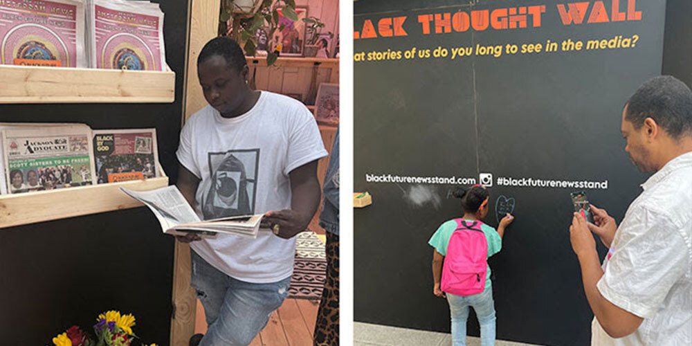 Two visitors at the Media 2070 "Black Future Newsstand" exhibit: a man on the left reading a newspaper and a child on the right writing on the Black Thought Wall