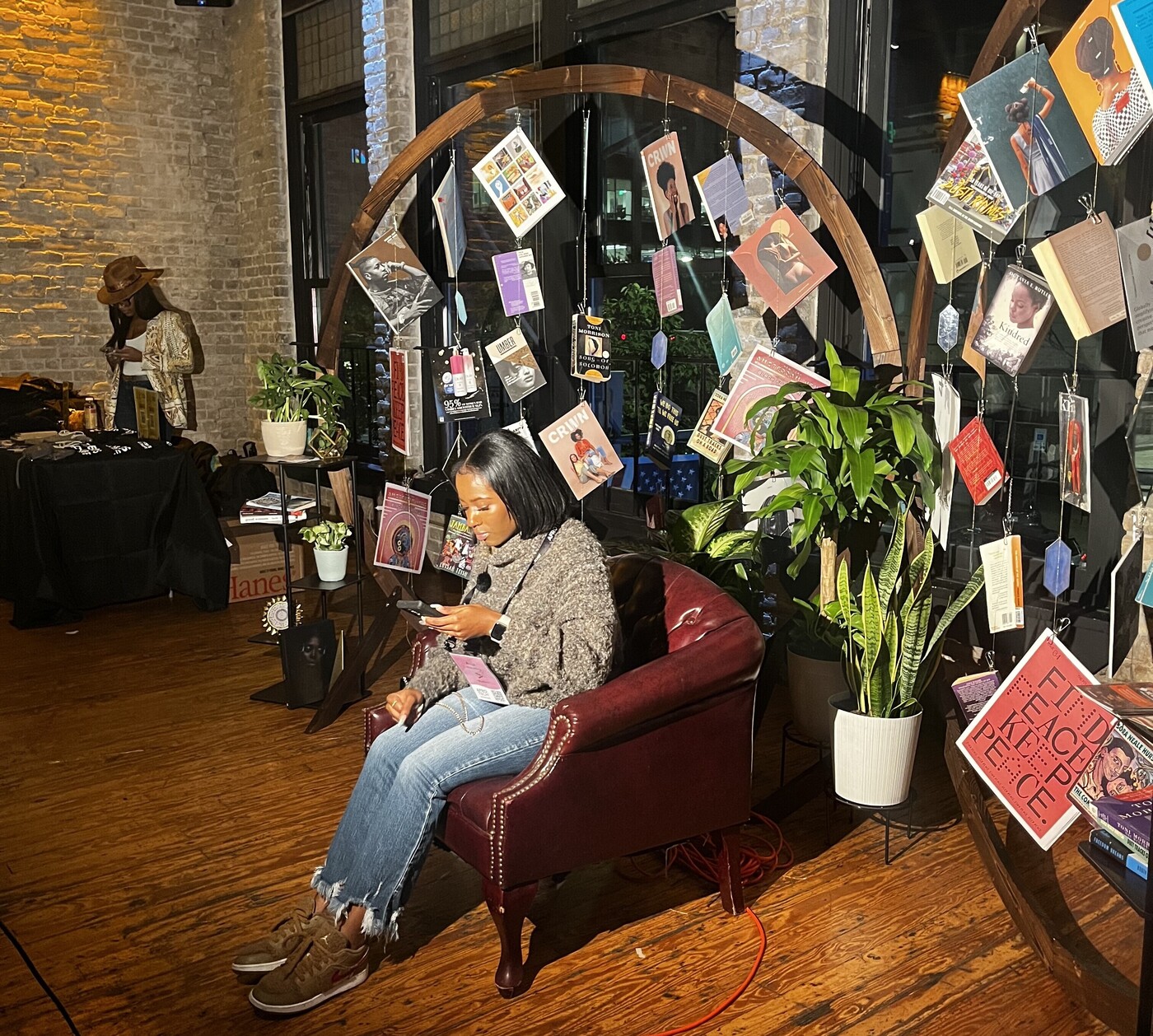 A person sitting in a chair and exploring the offerings at the Black Future Newsstand exhibit at AfroTech