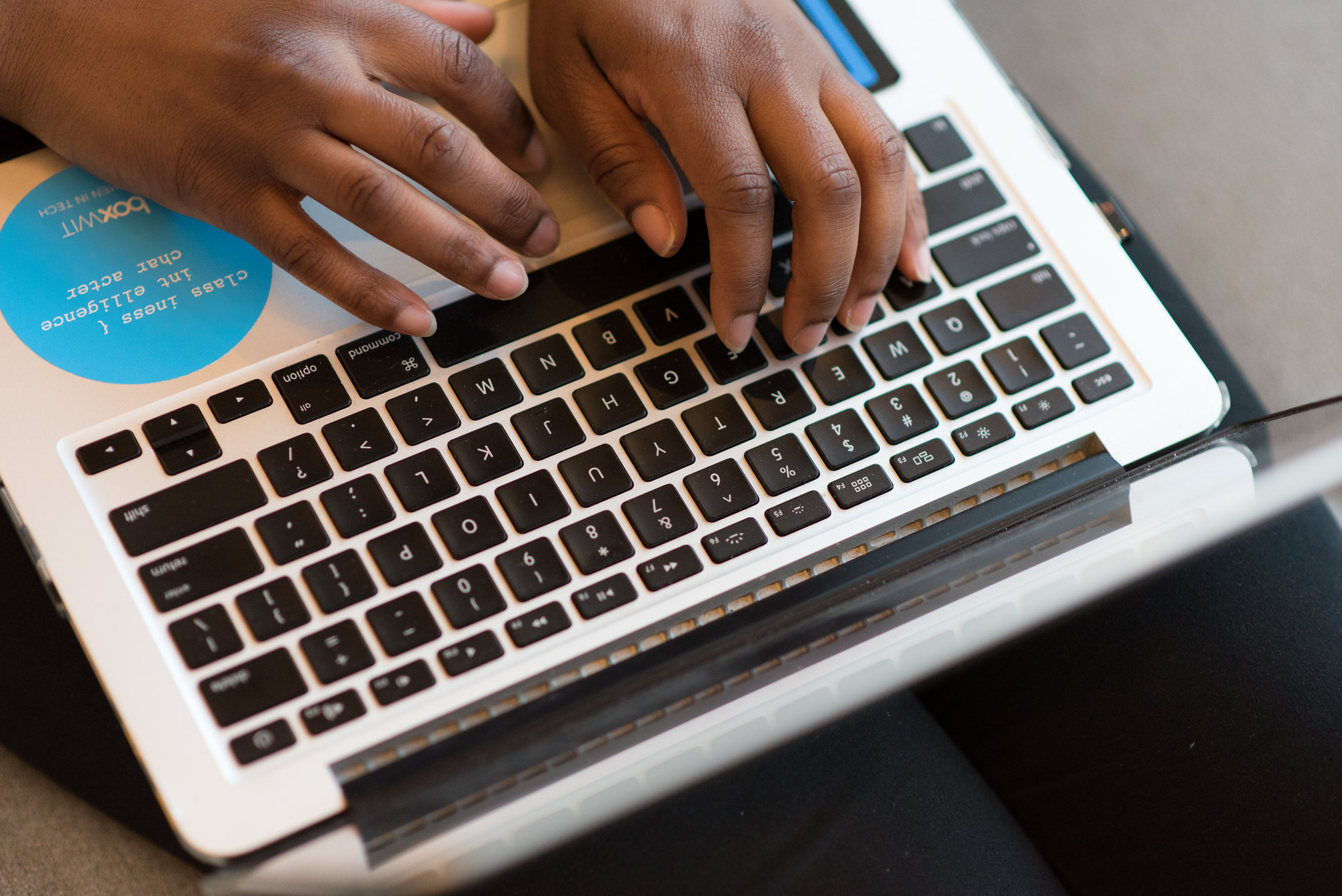 Photograph of a person typing on a laptop