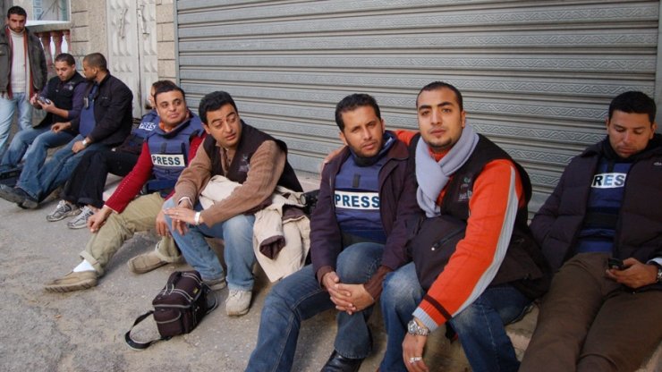 Journalists in Gaza sitting on the ground