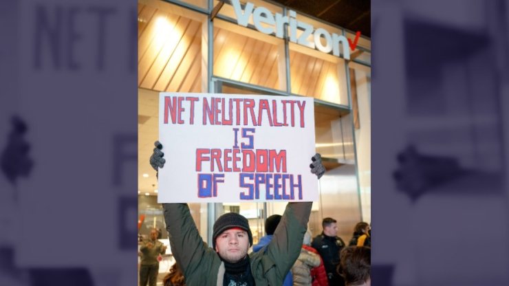 Net Neutrality activist in NYC holding a poster reading "Net Neutrality is freedom of speech"
