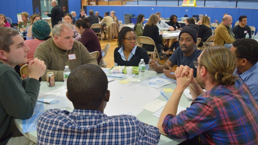 Man speaking at table with several other people