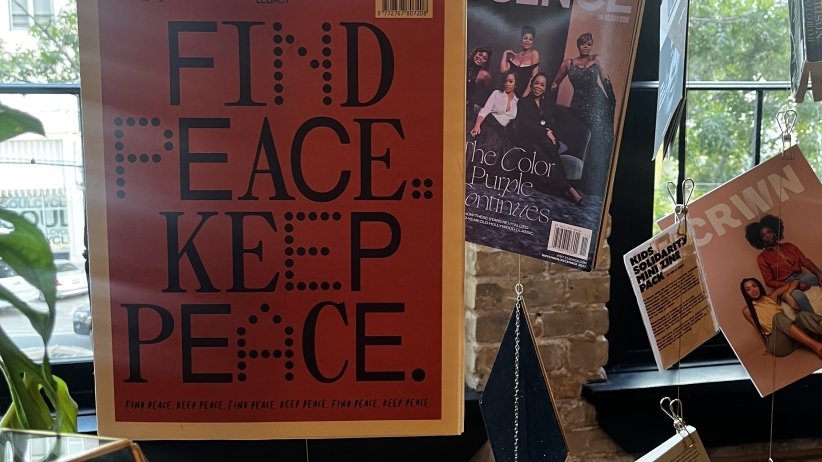 A display of Black-owned magazines and a "Find Peace Keep Peace" print at the Black Future Newsstand exhibit at AfroTech