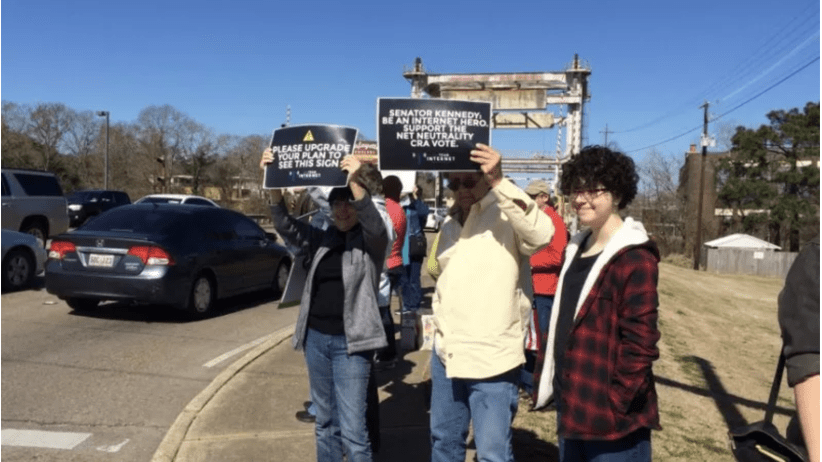 Net Neutrality activists holding signs by road