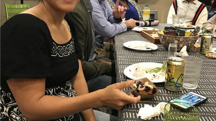 Woman smiling at camera with people eating meal in background