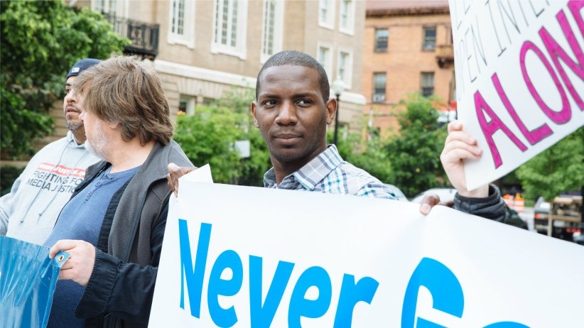 Man holding half-visible Net Neutrality sign