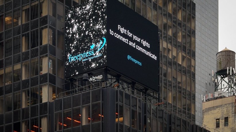 Video billboard reading "Fight for your rights to connect and communicate/@freepress"