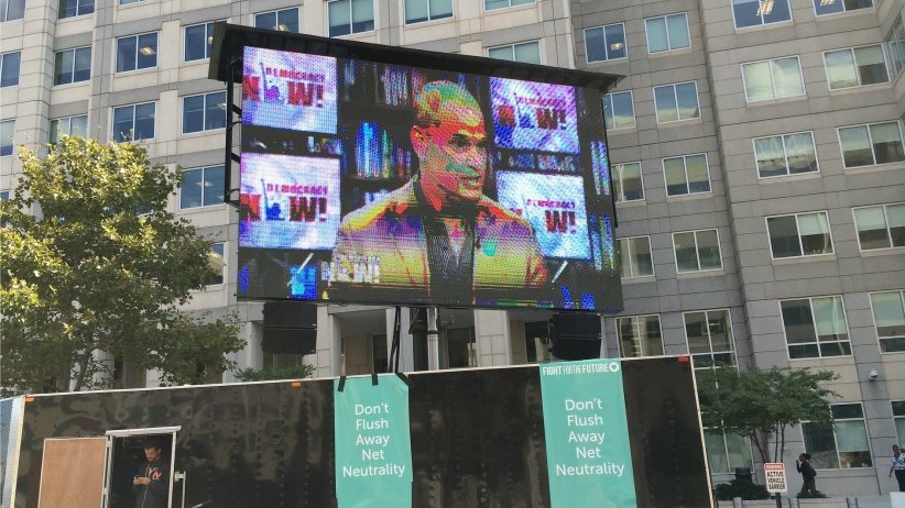 Billboard featuring image of man speaking on "Democracy Now!"