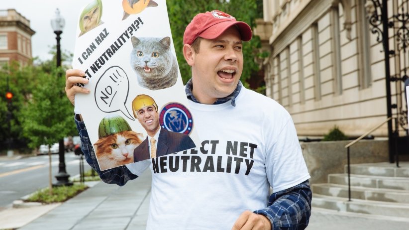 Activist holding sign reading "I can haz Net Neutrality?!?!"