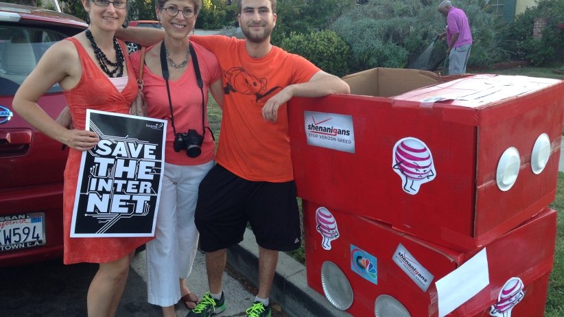 Three Net Neutrality activists standing beside an orange box