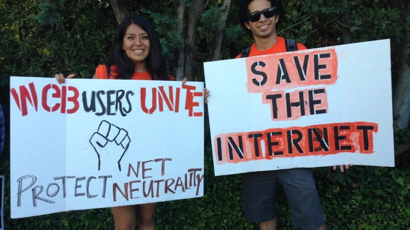 Activist holding "Web users unite" sign next to activist holding "save the internet" sign