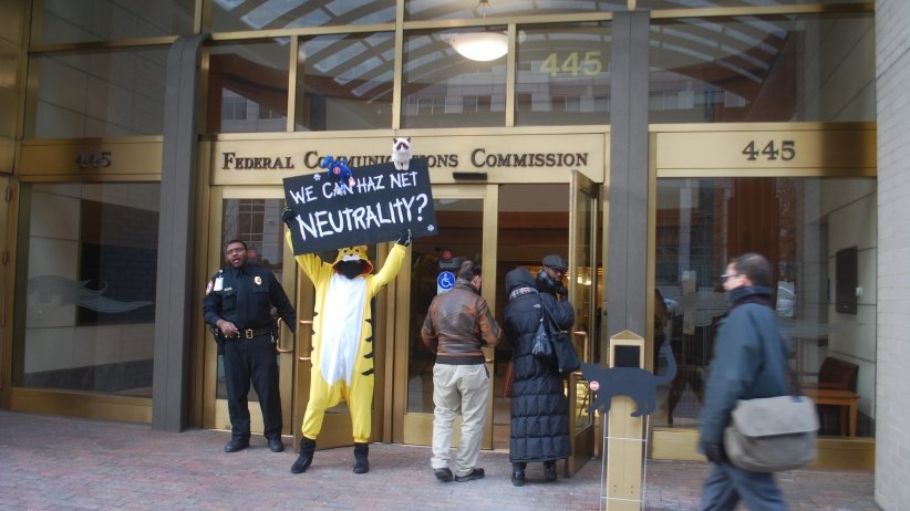 Person dressed as a cat standing in front of the FCC with sign reading "We can haz Net Neutrality?"