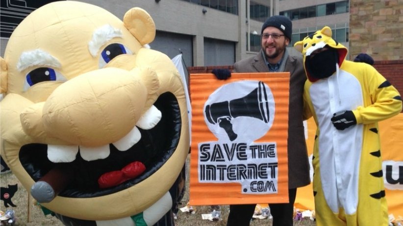 Person dressed as a greedy CEO standing next to Free Press President and CEO Craig Aaron and person dressed up as a cat