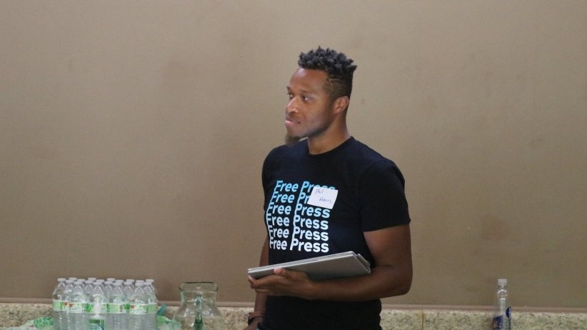 Man in Free Press T-shirt holding a notebook