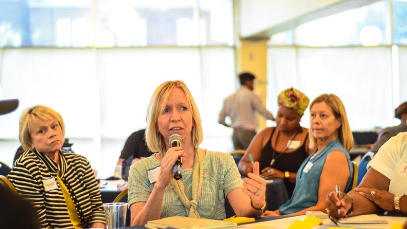 Woman seated at table speaks into a microphone