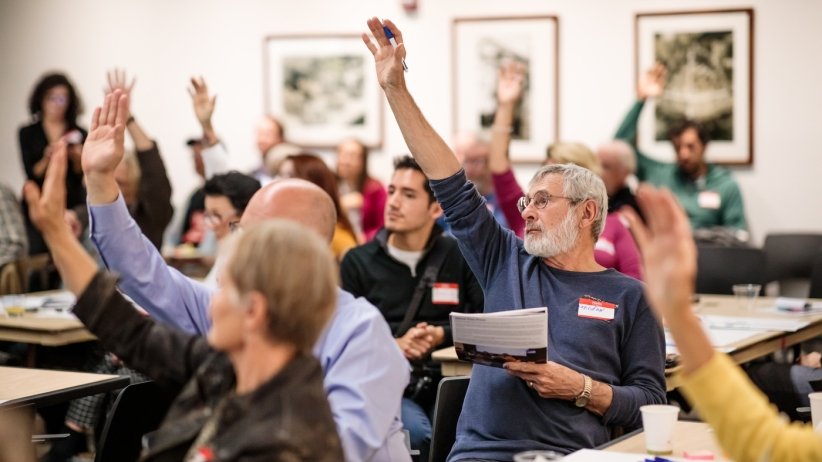 People raising their hands at the local-news gathering.