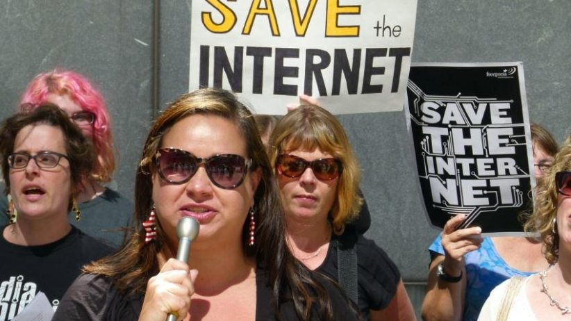 Woman speaking into microphone surrounded by other activists