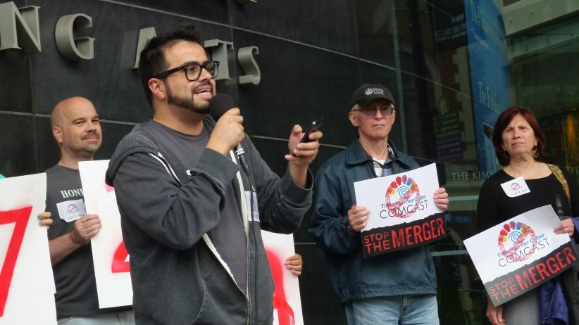 Man speaking into microphone while surrounded by other activists