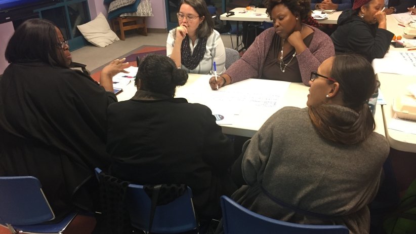 A group of women talk around a table