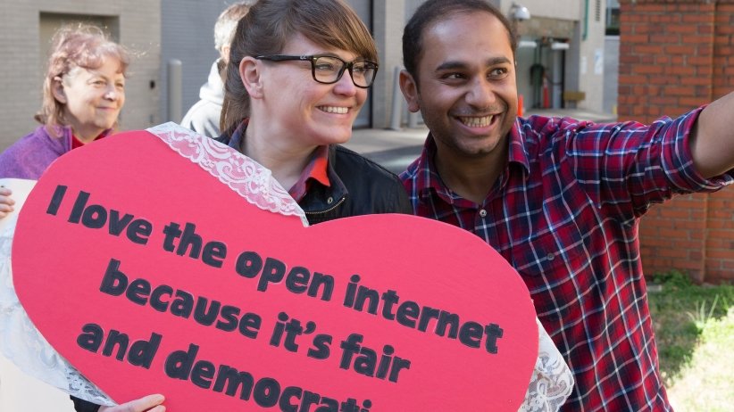 Two Free Press Action staffers holding valentine reading "I love the open internet because it's fair and democratic"