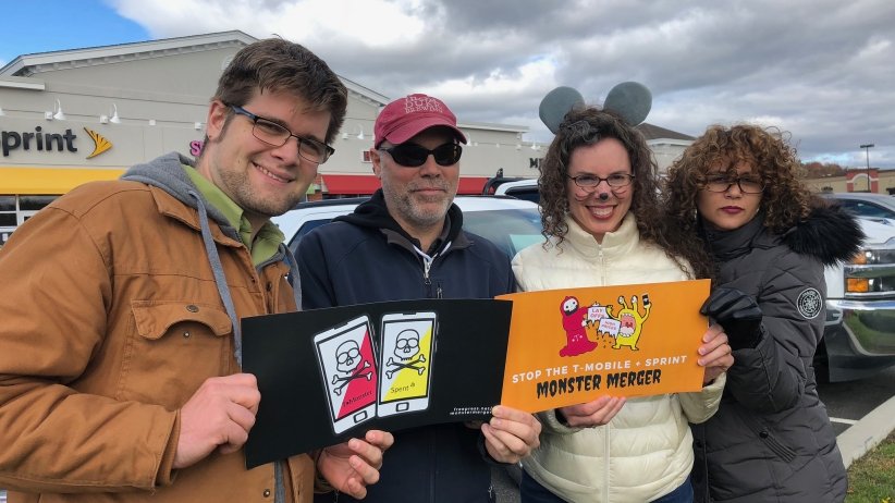 Four activists holding anti-merger signs
