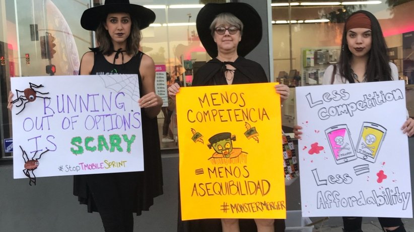 Three activists holding anti-merger signs
