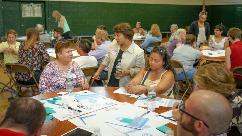 Two women talking at table filled with other people