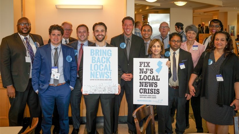 Activists holding signs reading "Bring back local news" and "Fix NJ's local news crisis"