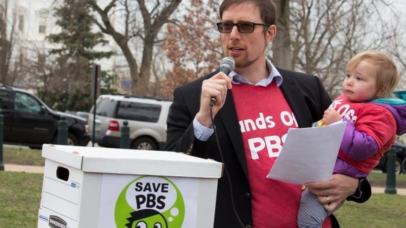 Ben Wikler of MoveOn speaking while holding his child