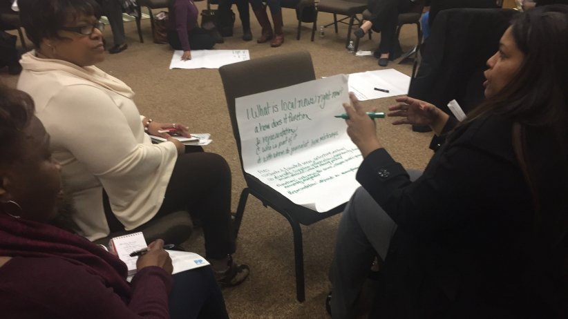 Two women brainstorming about the future of local news on a large writing pad