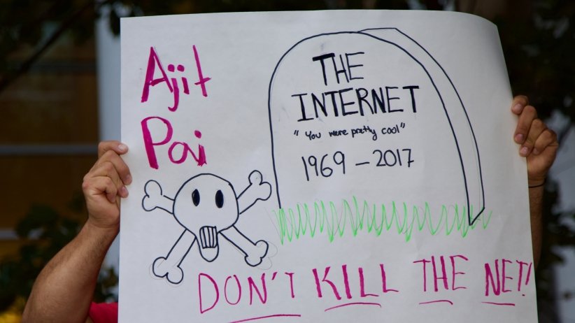 Activist holding poster with the words "Ajit Pai: Don't kill the net!"