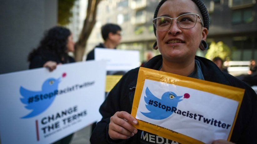 Activist holding a sign reading "Stop Racist Twitter"