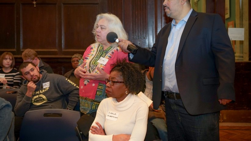 Free Press' Joseph Torres extends the microphone to a woman