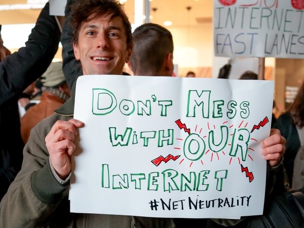 A photo of a person holding up a sign that says "don't mess with our internet"