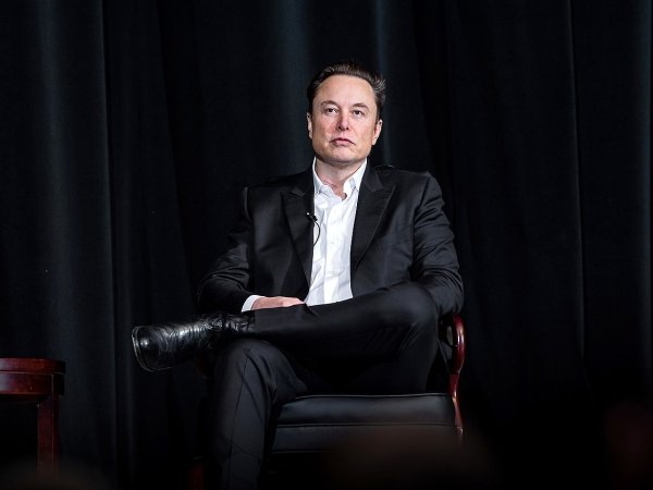 Twitter CEO Elon Musk sitting in a chair against a black background