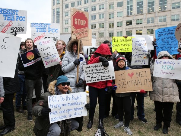 Net Neutrality activists holding signs with messages like "FCC, do the right thing and maintain a free and open internet accessible to all"