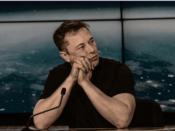 Elon Musk sitting at a microphone