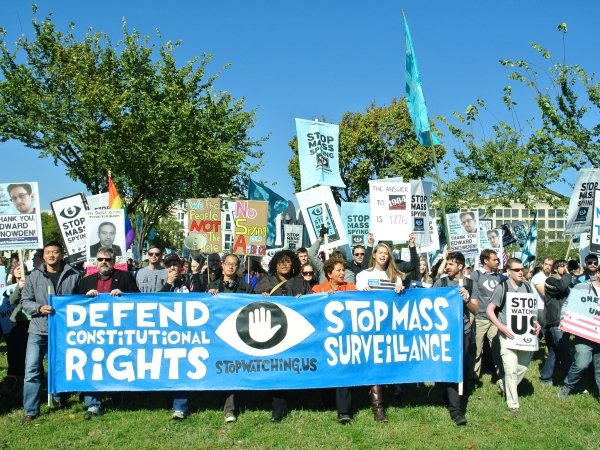 Protesters holding banner reading "Defend Our Rights. Stop Mass Surveillance."