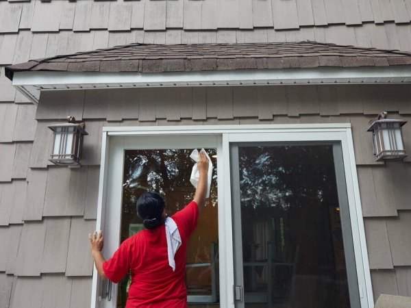 Maricela Bendito washing the windows of a house in New Jersey.