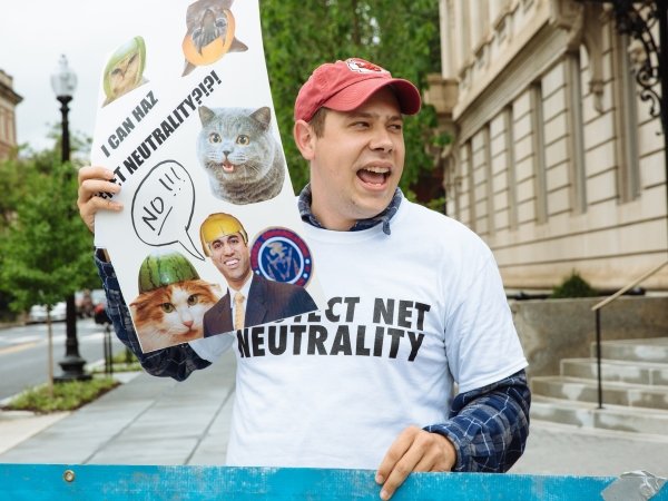 Activist holding sign reading "I can haz Net Neutrality?!?!"