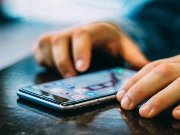 Hands resting on table on either side of cellphone
