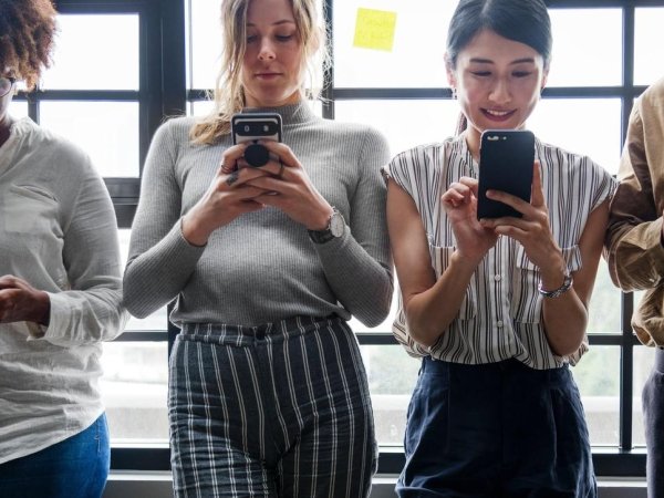 Three women and one man using their phones