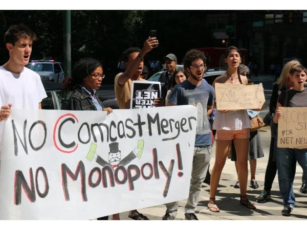 Philly activists holding poster reading "No Comcast merger / no monopoly!"