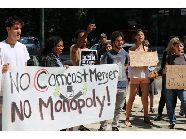 Activists holding banner reading "No Comcast merger / no monopoly"
