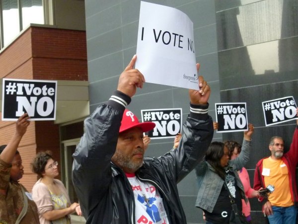 Man holding "I vote no!" sign surrounded by other activists