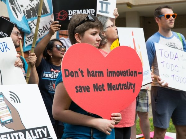 Net Neutrality rally featuring woman holding sign reading "Don't harm innovation / save Net Neutrality"