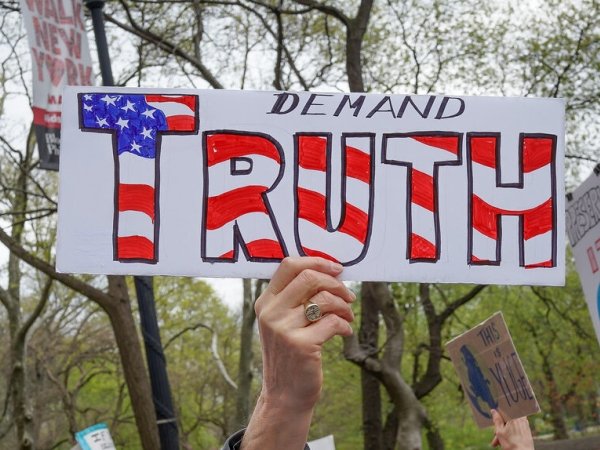 Protester holding a sign reading "Demand truth"