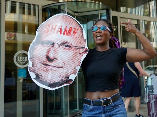 Activist holding a sign with a photo of FCC Chairman Carr and the word "Shame"